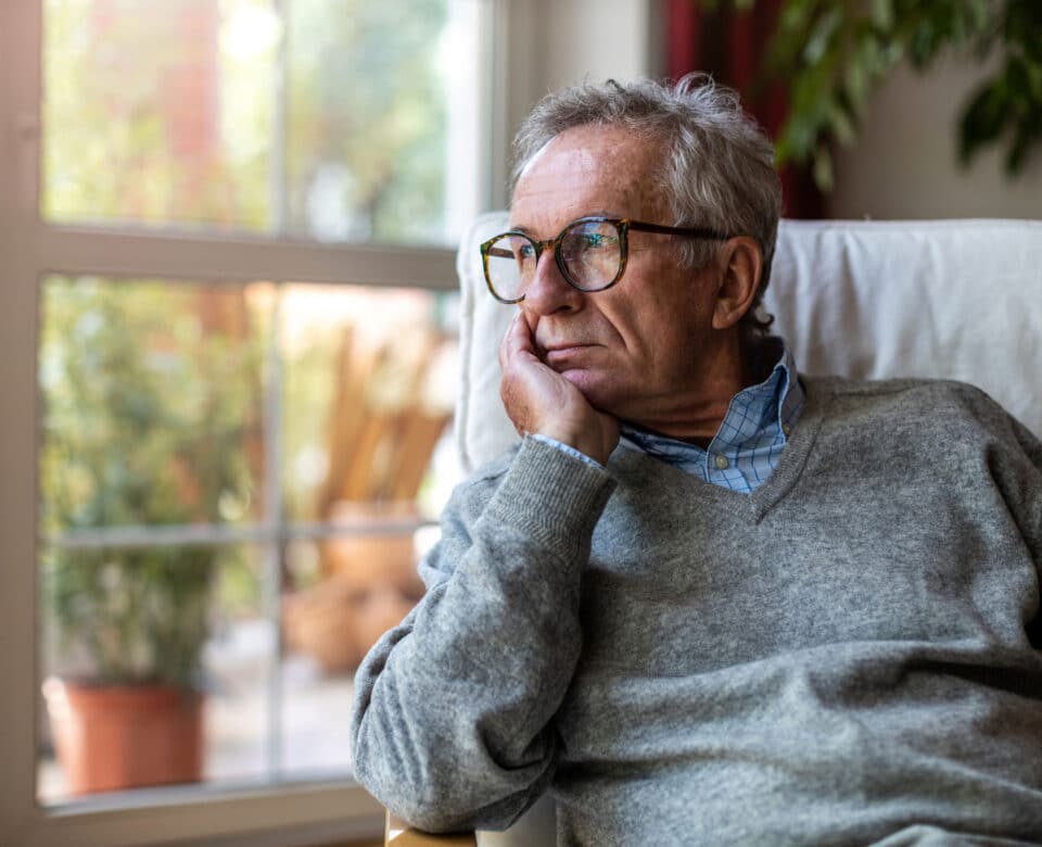 En mand der sidder og kigger ud af et vindue